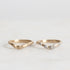 two gold curved rings, one with diamonds, on a light gray background