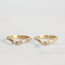 Two gold rings with small diamonds on a light gray background