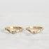 Two gold rings with small diamonds on a light gray background