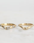 Two gold rings with small diamonds on a light gray background