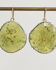 Green stone earrings on a thin rod against a light gray background