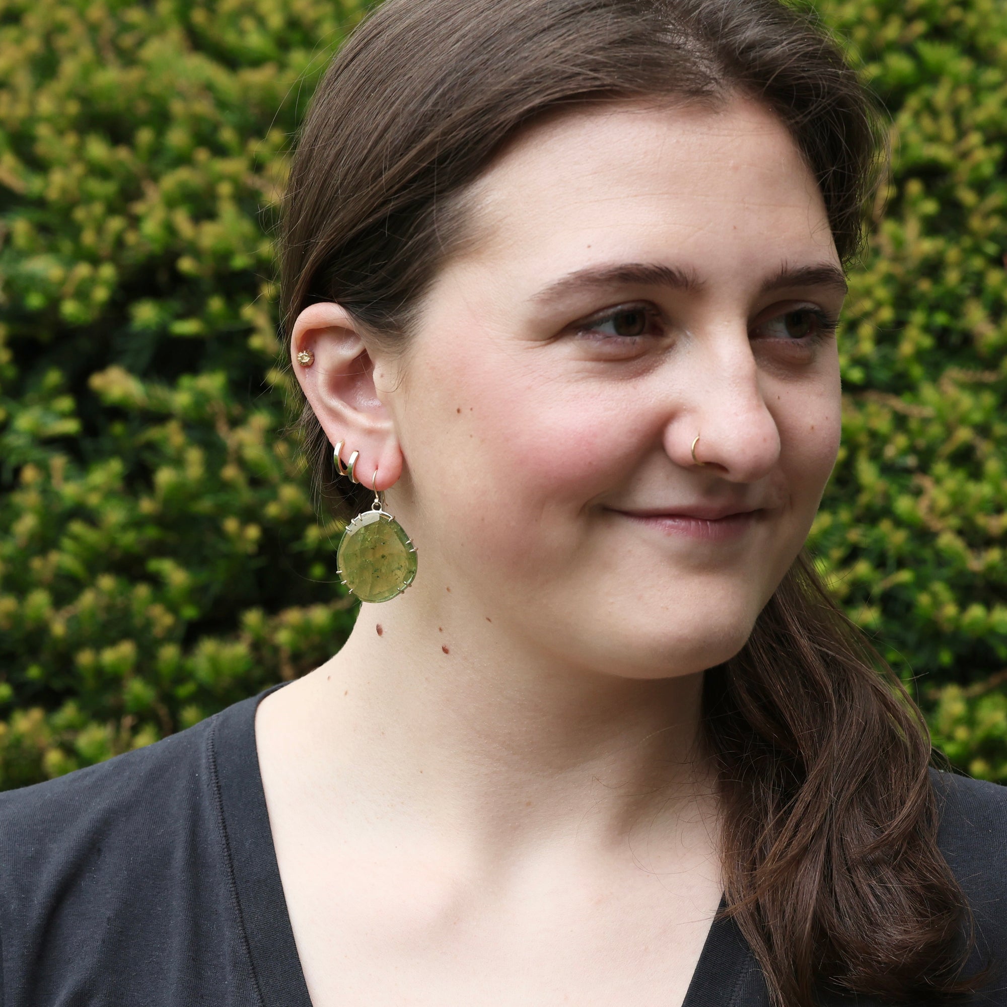 woman wearing large green gemstone earrings
