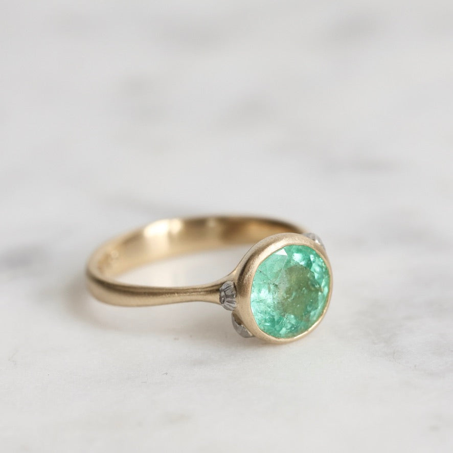 Gold ring with a green gemstone on a light background