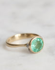Gold ring with a green gemstone on a light background