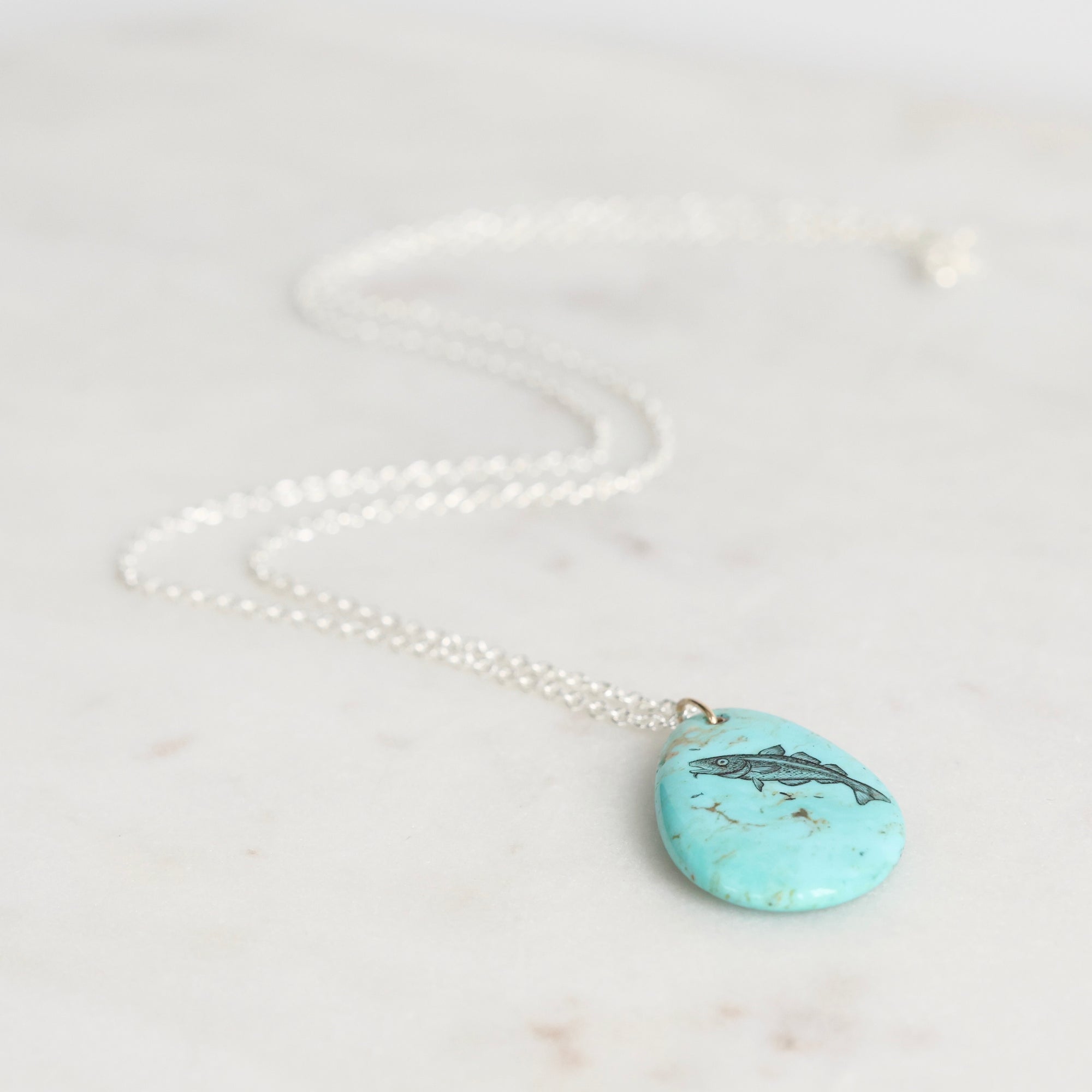 Turquoise pendant necklace on a marble surface
