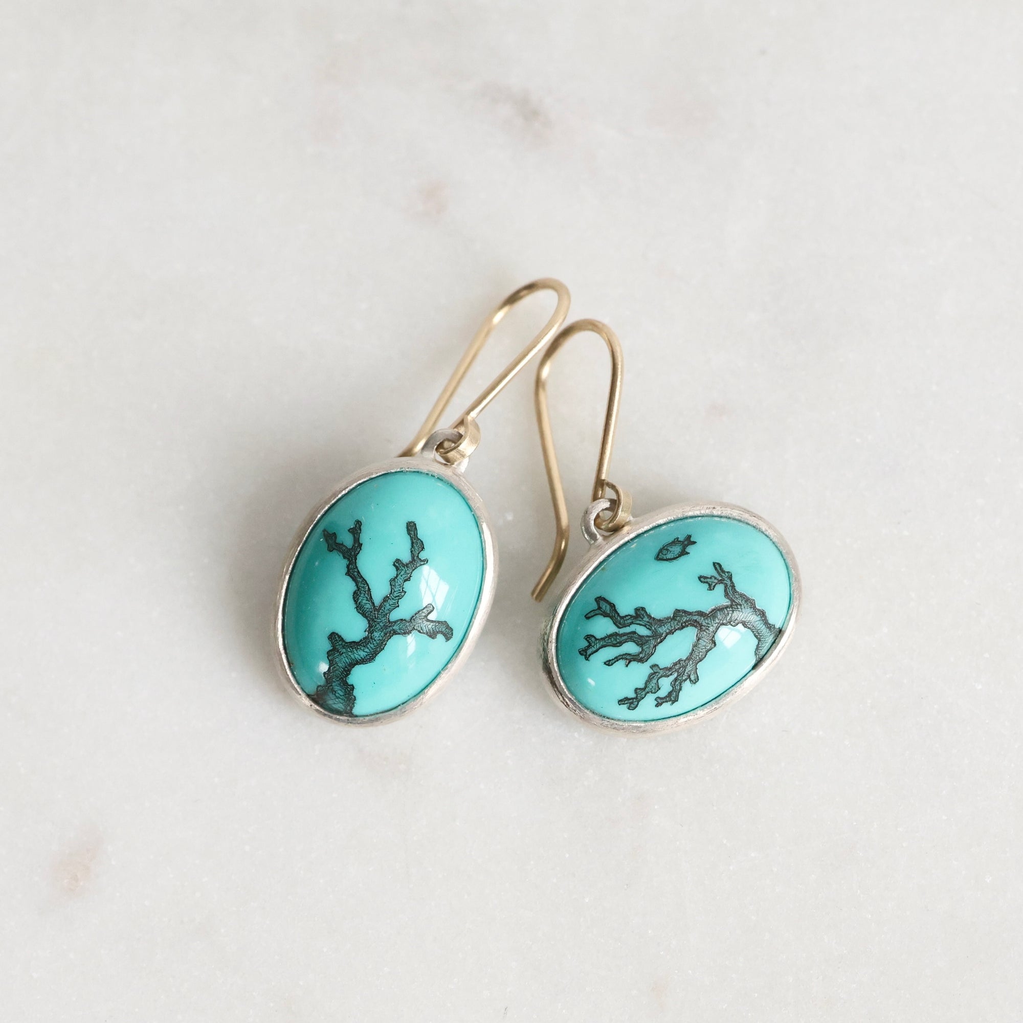 Turquoise earrings with silver accents on a light gray background