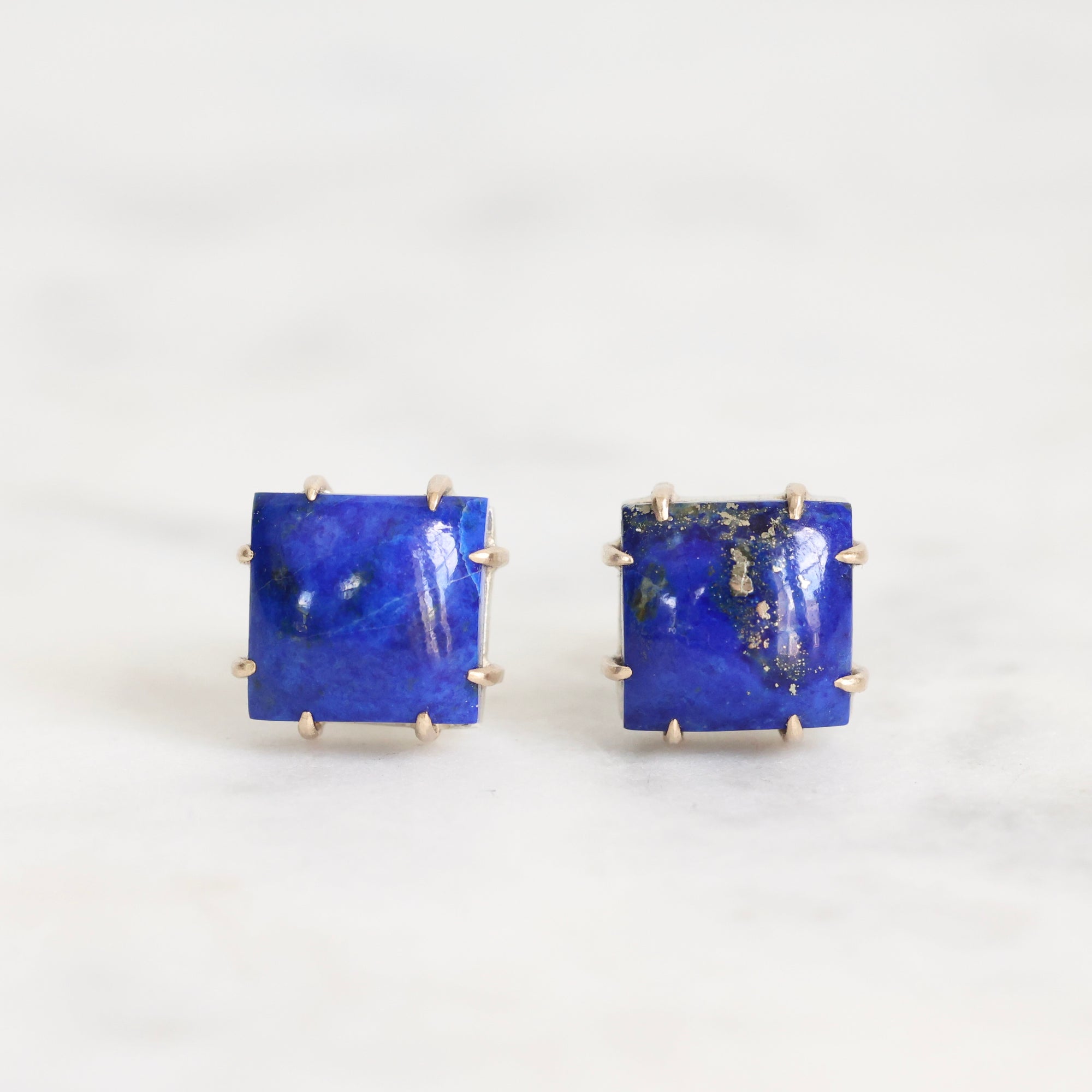 Pair of square blue gemstone earrings on a white background