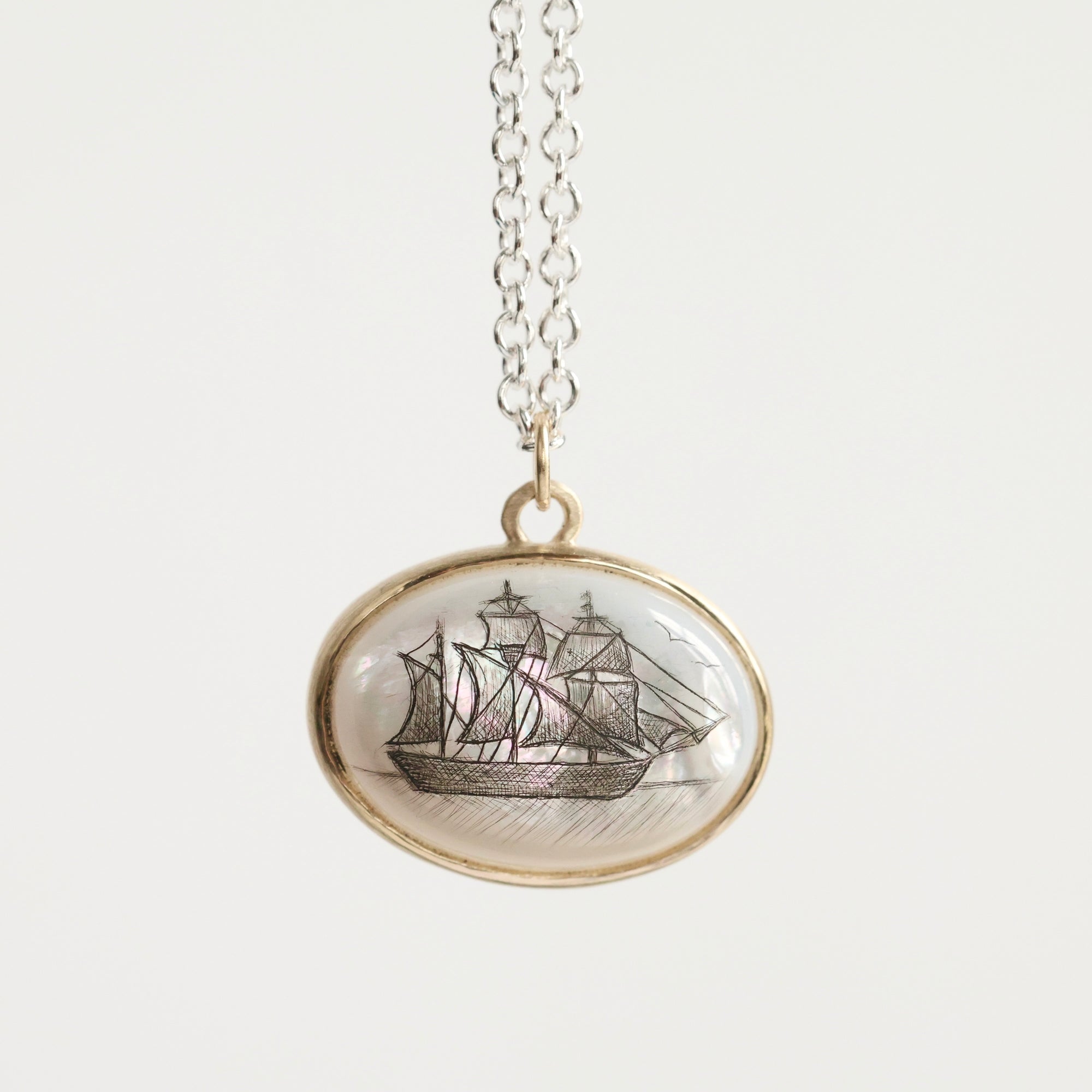 Necklace with a pendant featuring a ship design on a white background