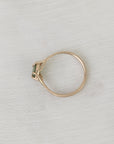 Gold ring with a green gemstone on a light gray fabric background
