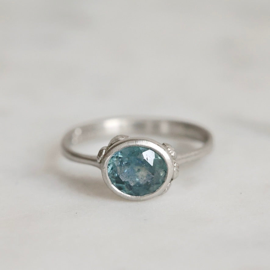 Silver ring with a blue gemstone on a light gray background