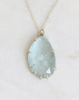 Necklace with a large teardrop-shaped green stone on a light gray background