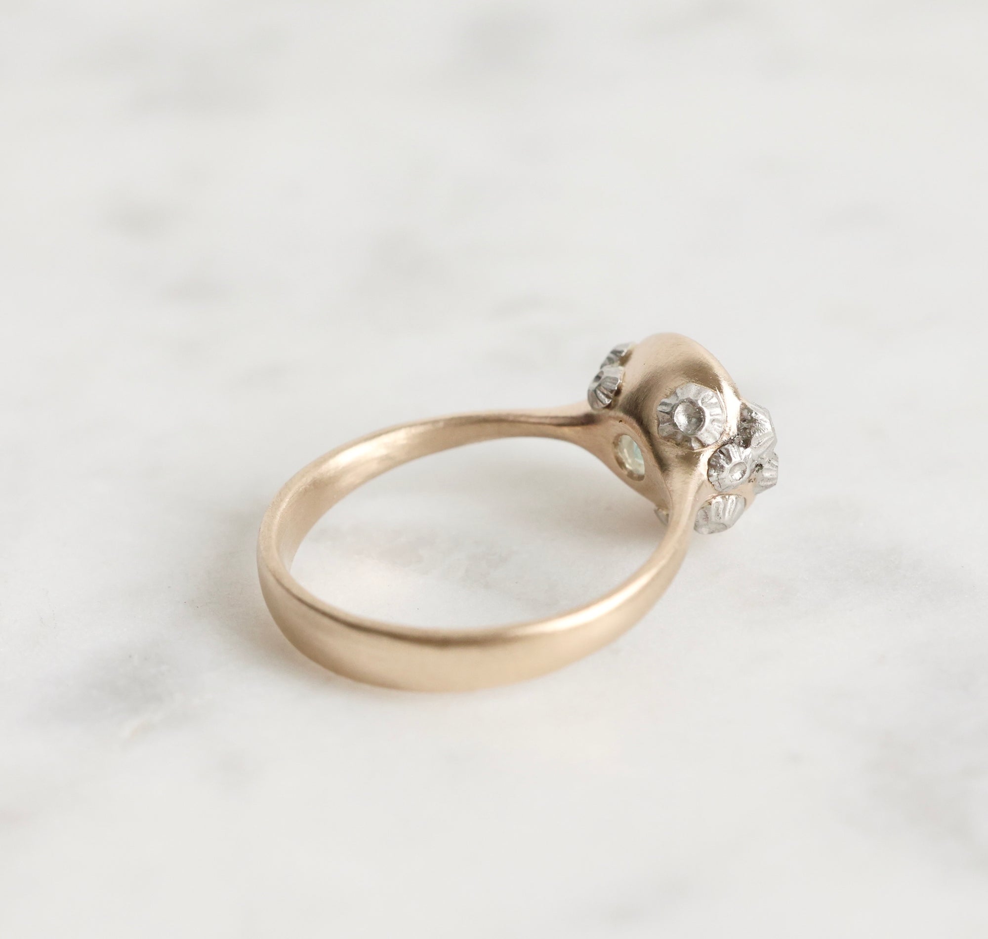 Gold ring with a small diamond on a light gray background