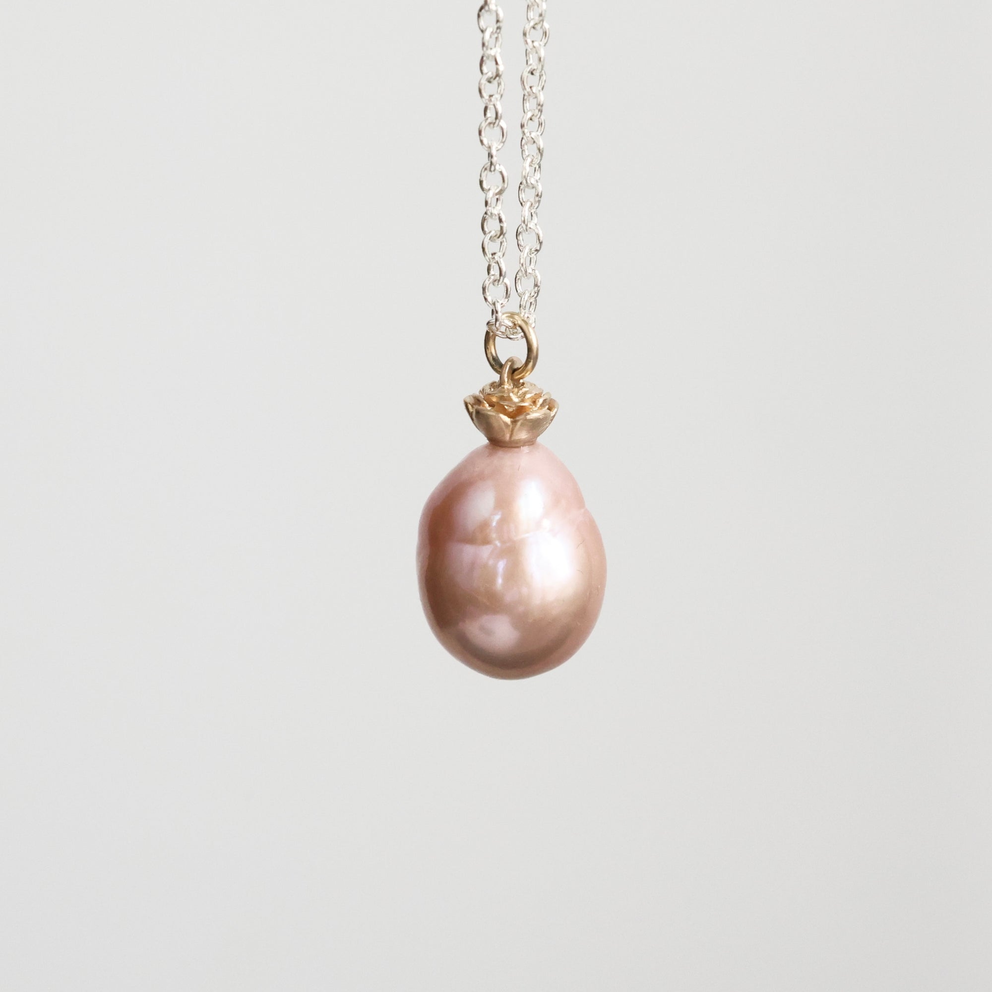 Pearl necklace with a gold clasp on a light gray background
