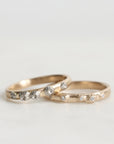 Two gold rings with diamond accents on a light gray background