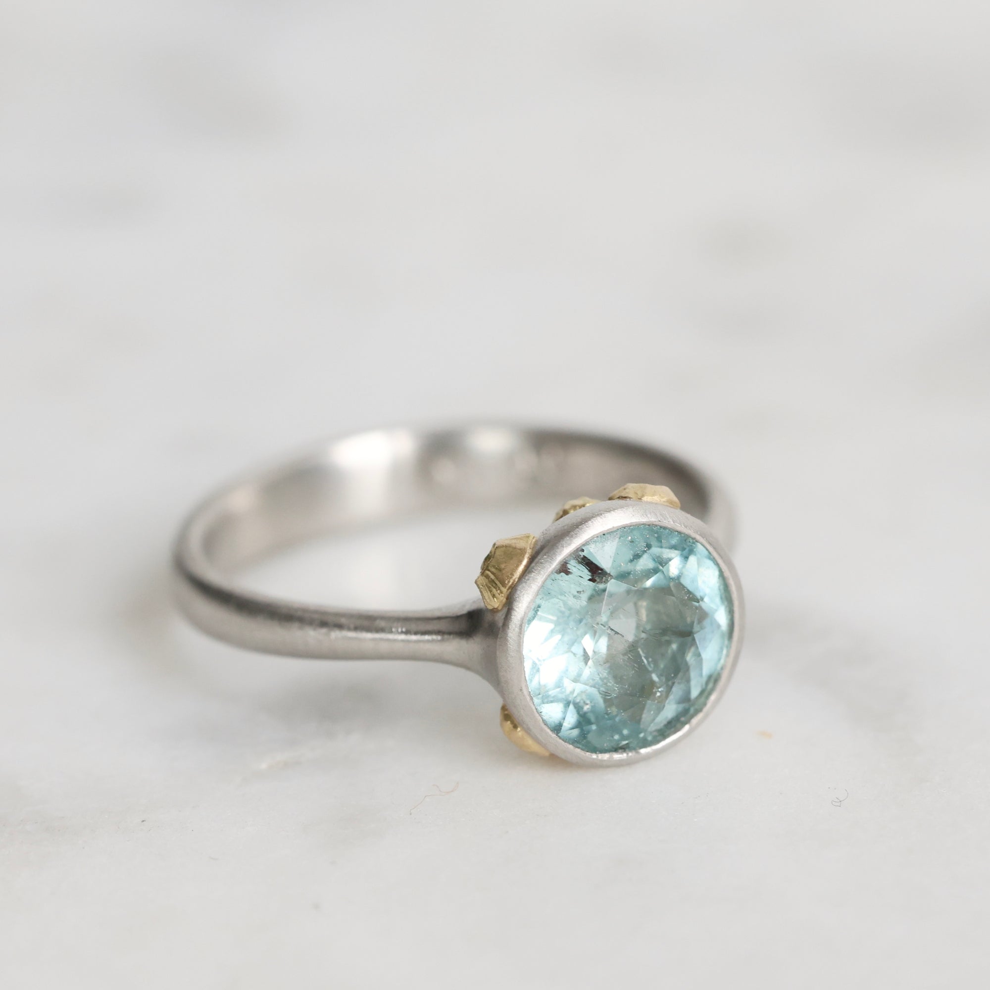 Silver ring with a blue gemstone on a light gray background
