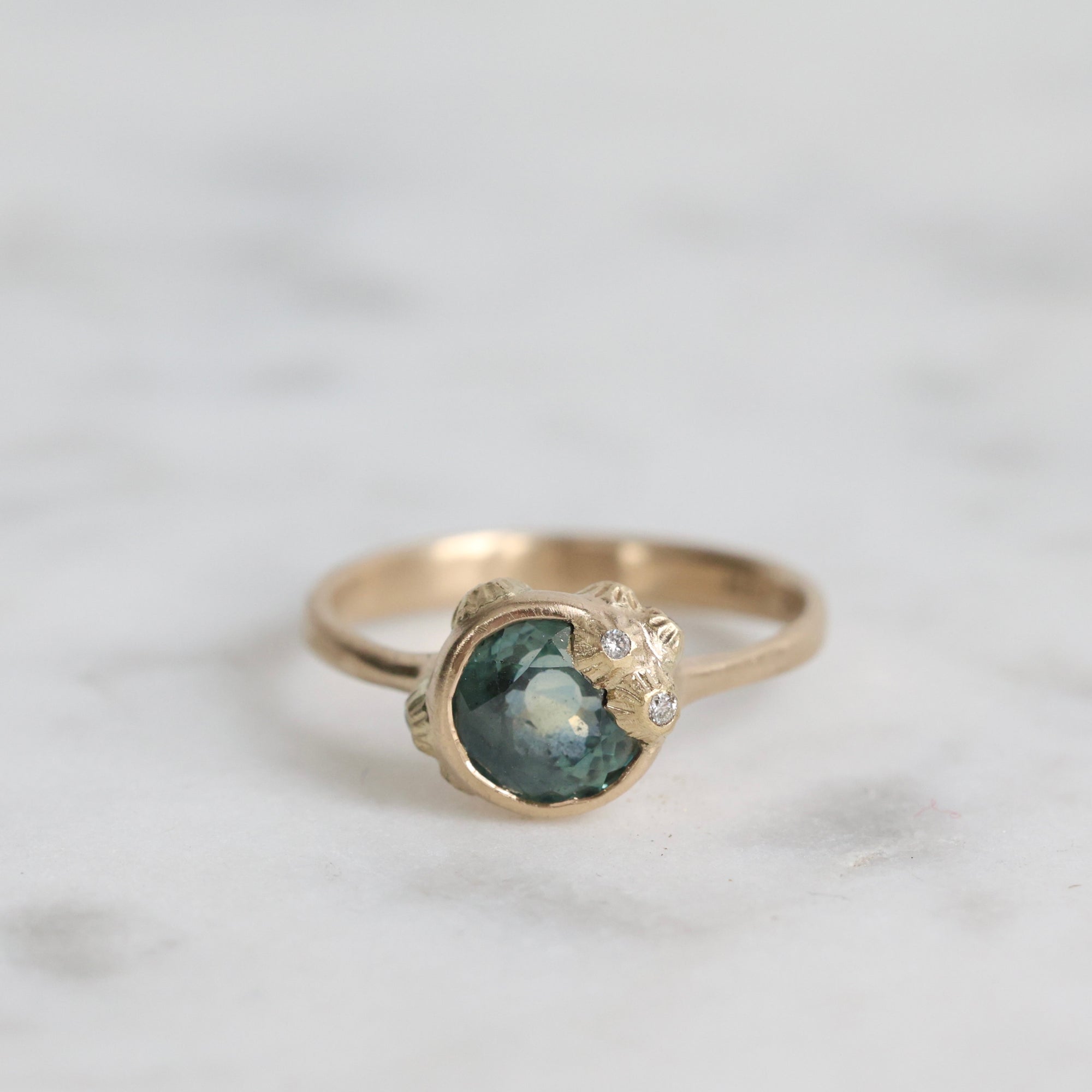 Gold ring with a green gemstone on a light gray background