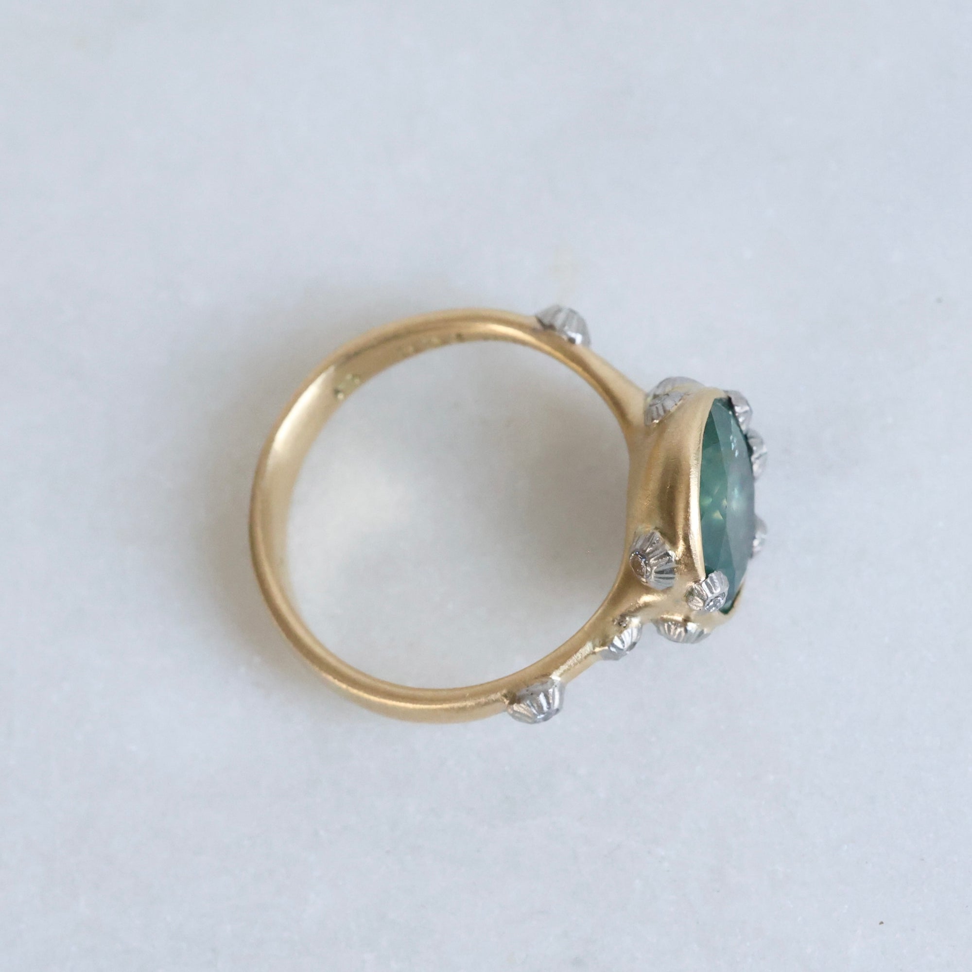 Large green sapphire ring with lots of barnacles. Gold shank