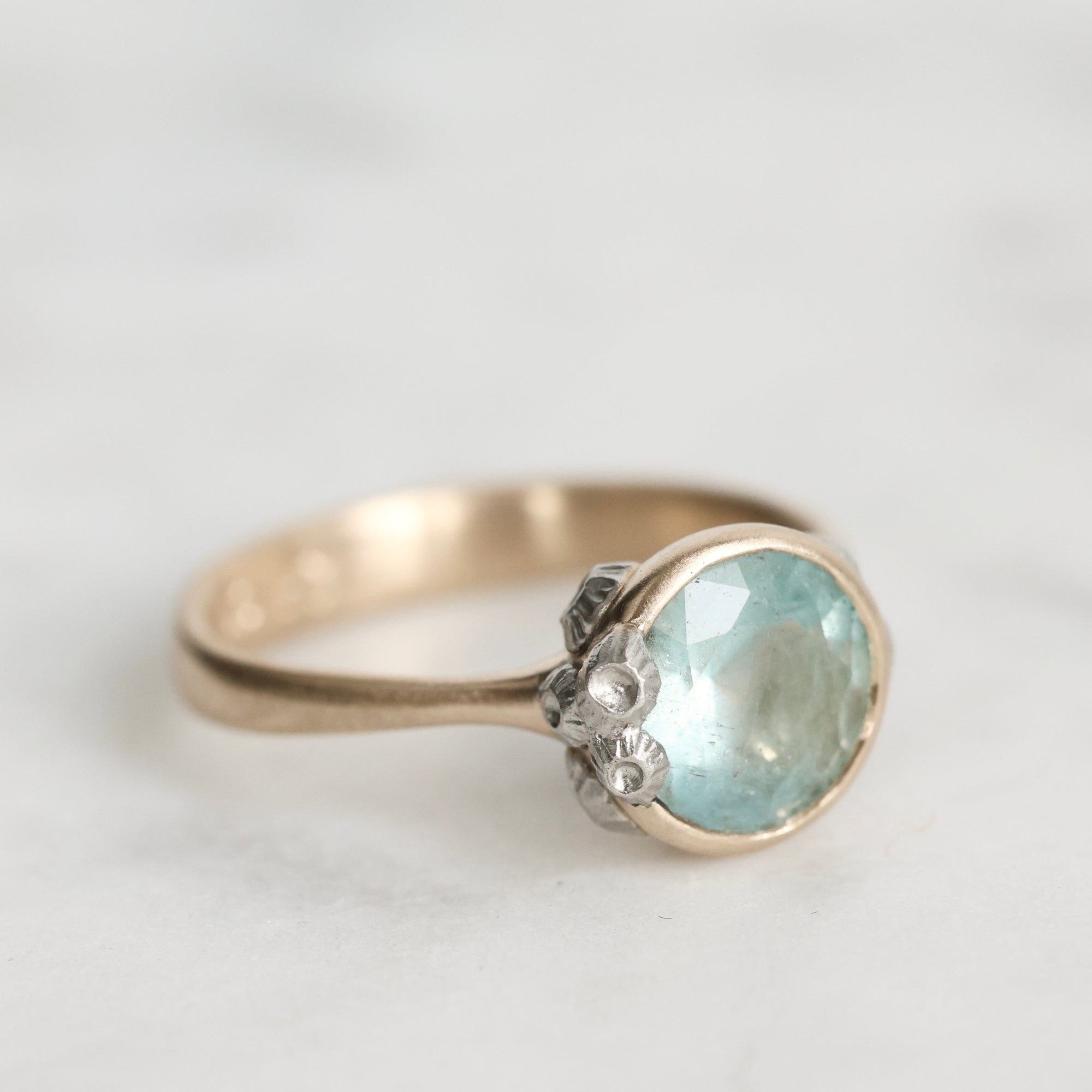 Silver ring with a light blue gemstone on a white background