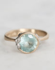 Gold ring with a large green gemstone on a light gray background