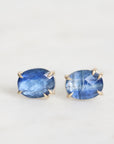 Pair of blue gemstone earrings with gold settings on a white background