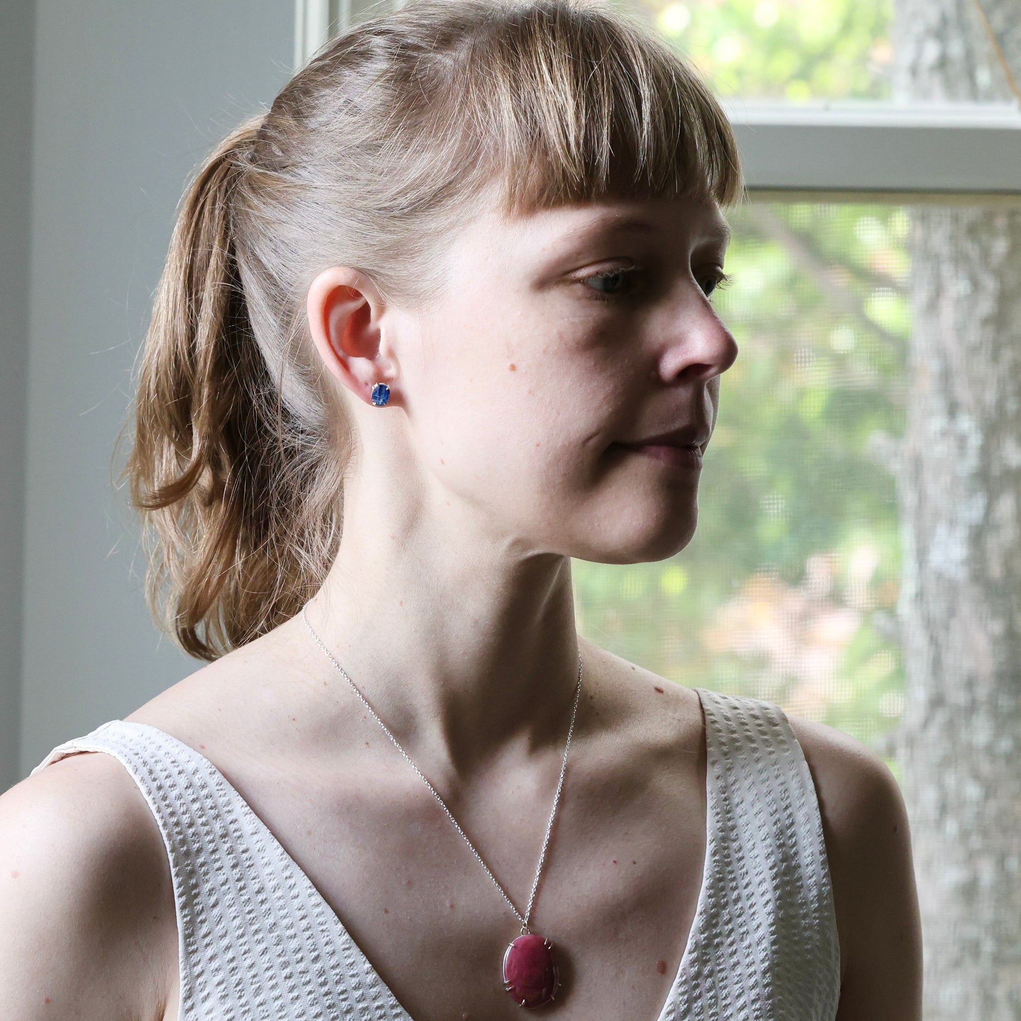 Woman wearing a necklace with a red pendant in front of a window