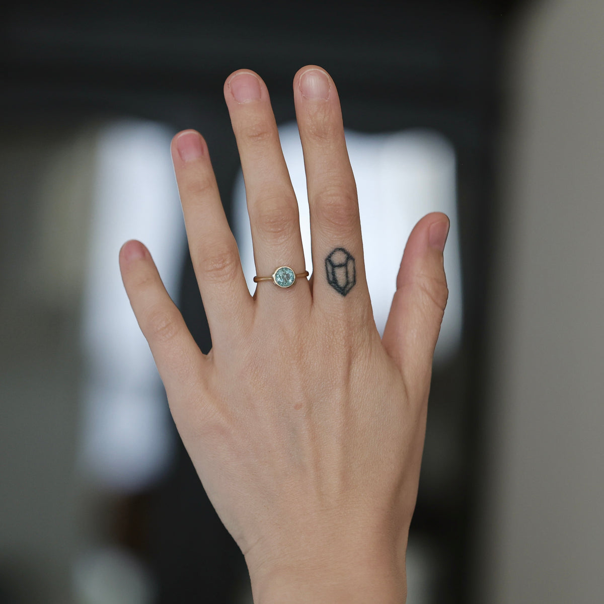 Hand wearing blue gemstone ring. 
