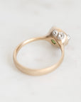 A vintage-style ring with a yellow gold band, a silver-toned setting, and small clear gemstones, photographed on a light marble surface.