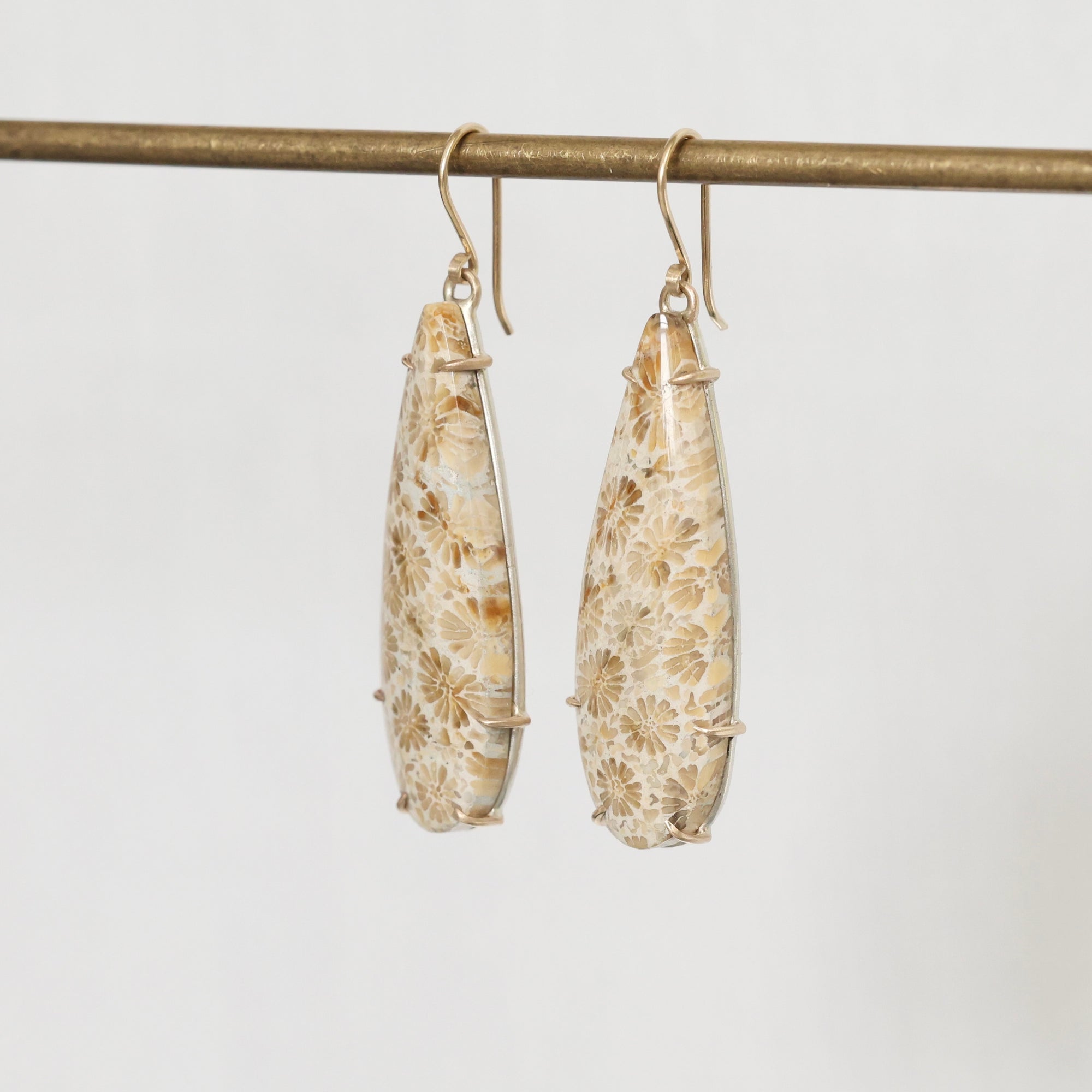 Pair of floral teardrop earrings on a thin rod against a light background