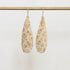 Pair of floral-patterned earrings on a gold rod against a light background
