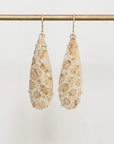 Pair of floral-patterned earrings on a gold rod against a light background
