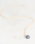 Opal necklace set in yellow gold with a yellow gold chain laying on a plain background. 