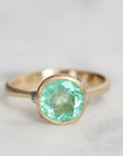 Gold ring with a green gemstone on a light gray background