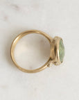 Gold ring with a green gemstone on a light gray background