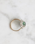 Gold ring with a green gemstone on a marble surface