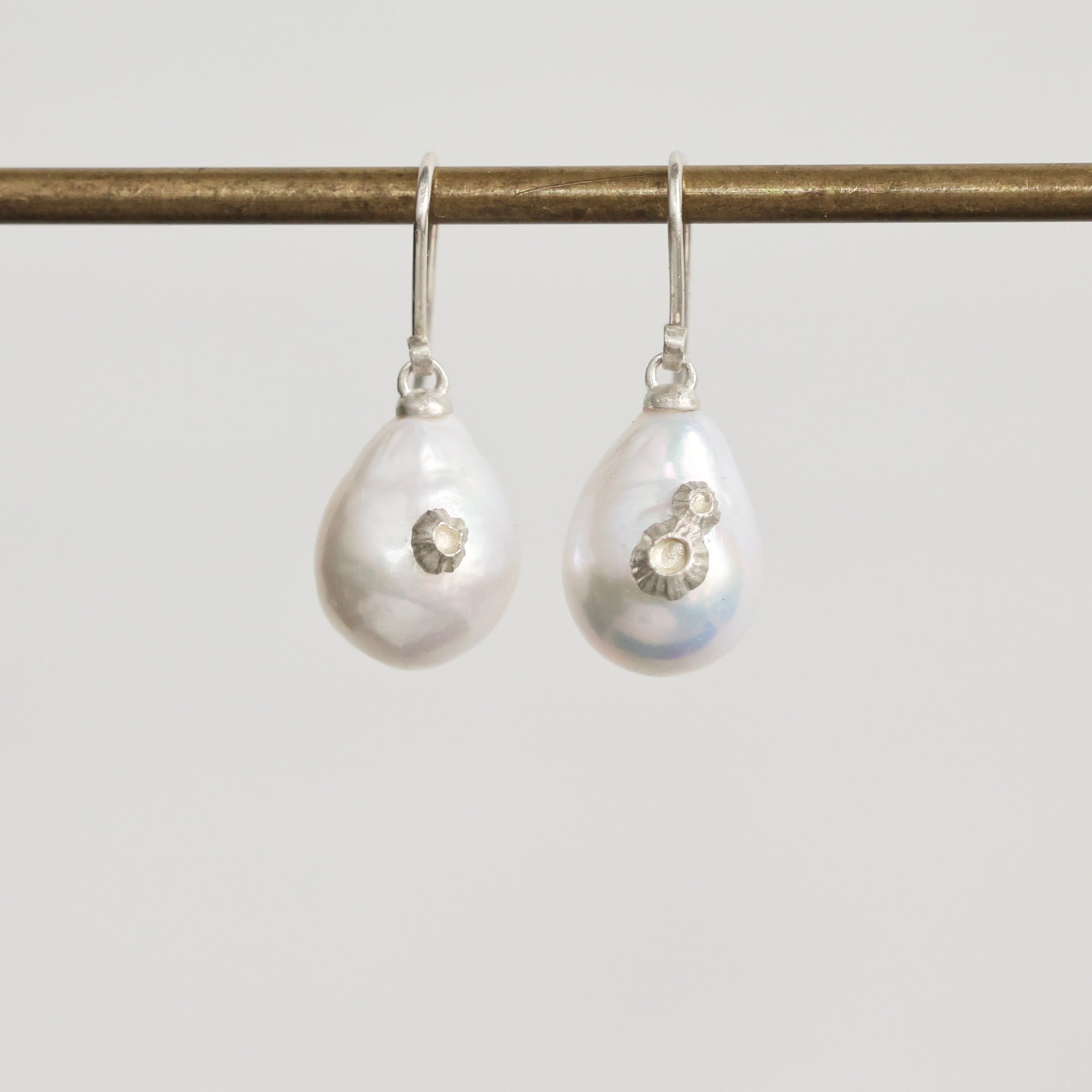 Pair of pearl earrings with silver accents on a white background