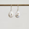 Pair of pearl earrings with silver accents on a white background