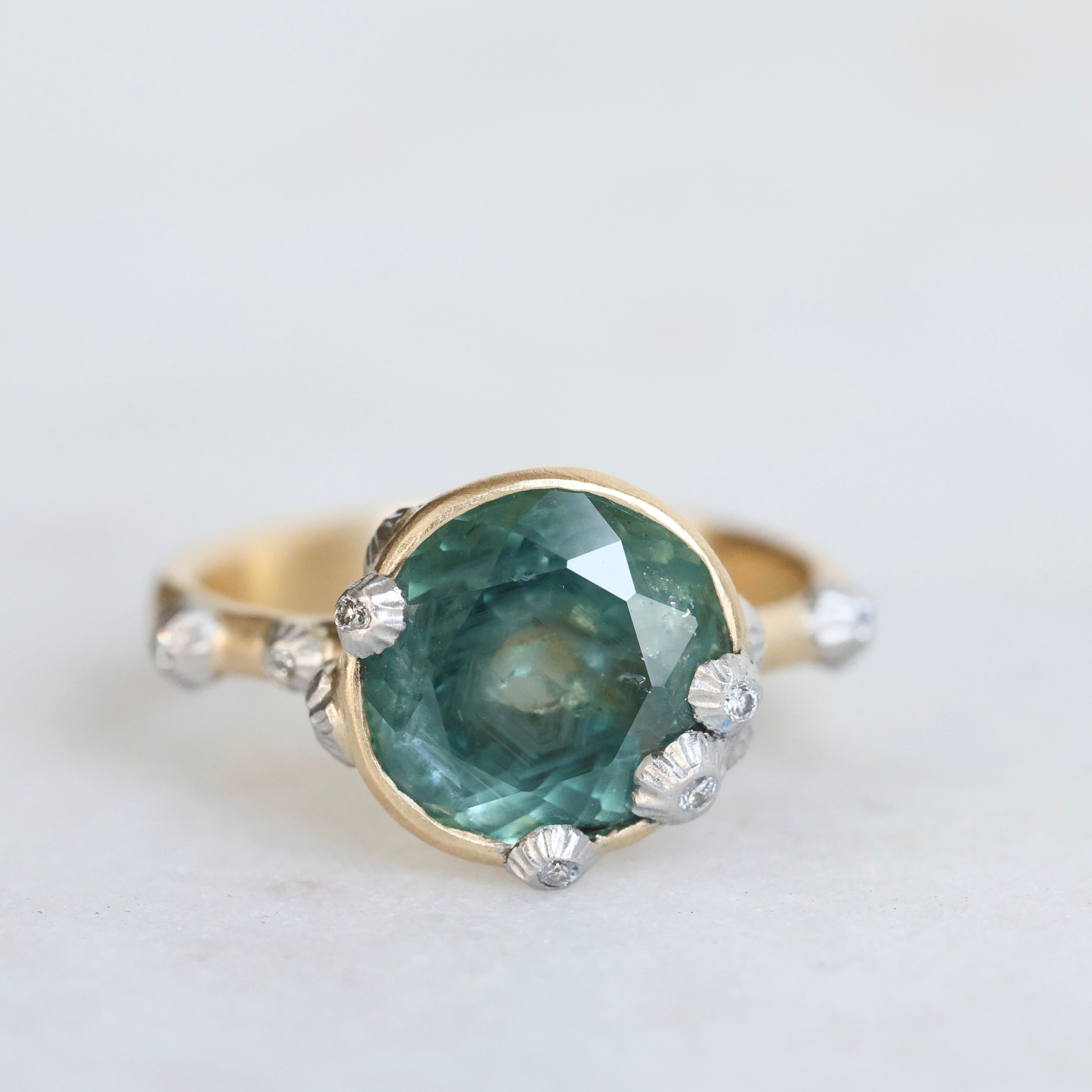 Large green sapphire ring with lots of barnacles. Gold shank. 