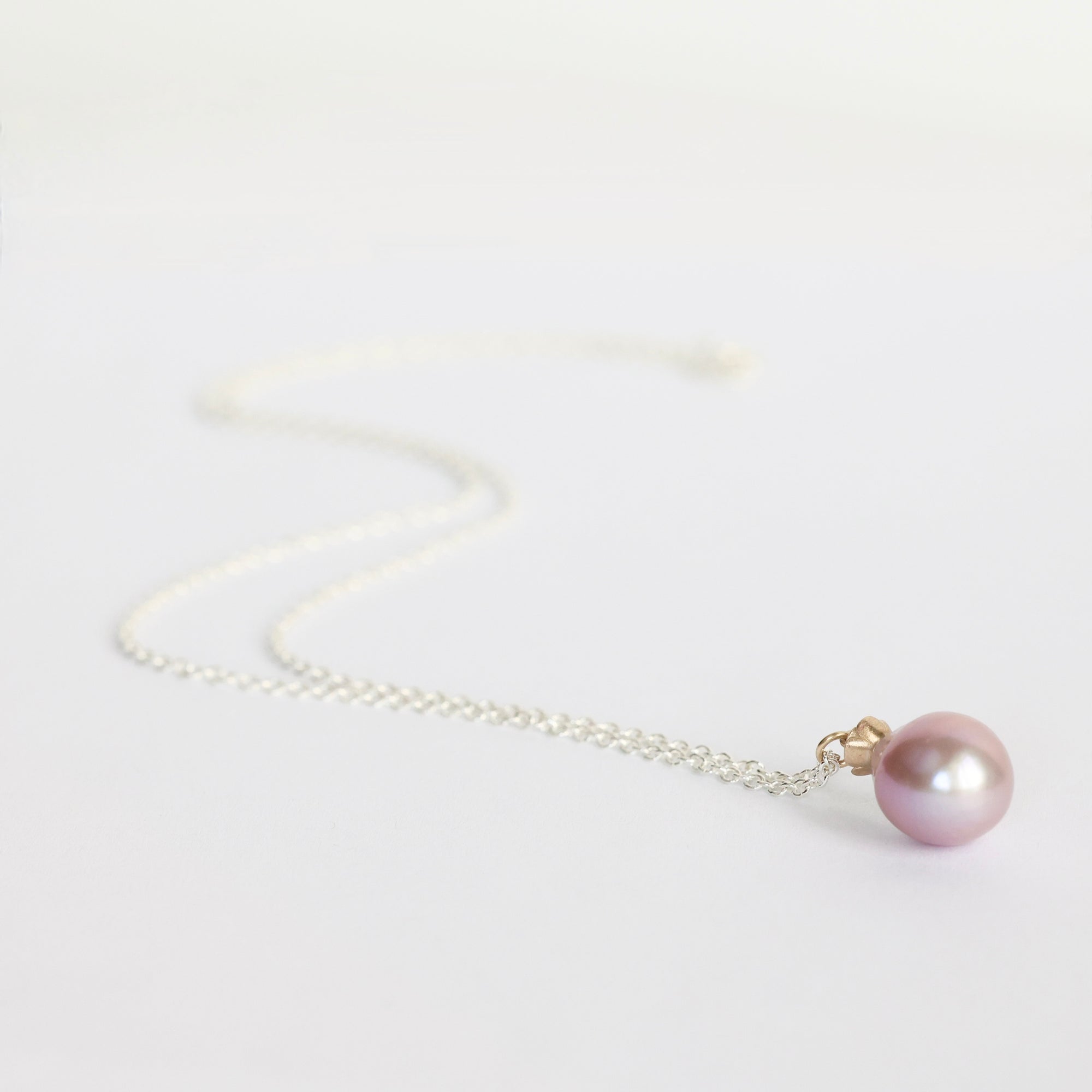 Necklace with a pink pearl pendant on a light gray background