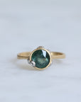 Gold ring with a green gemstone on a light gray background
