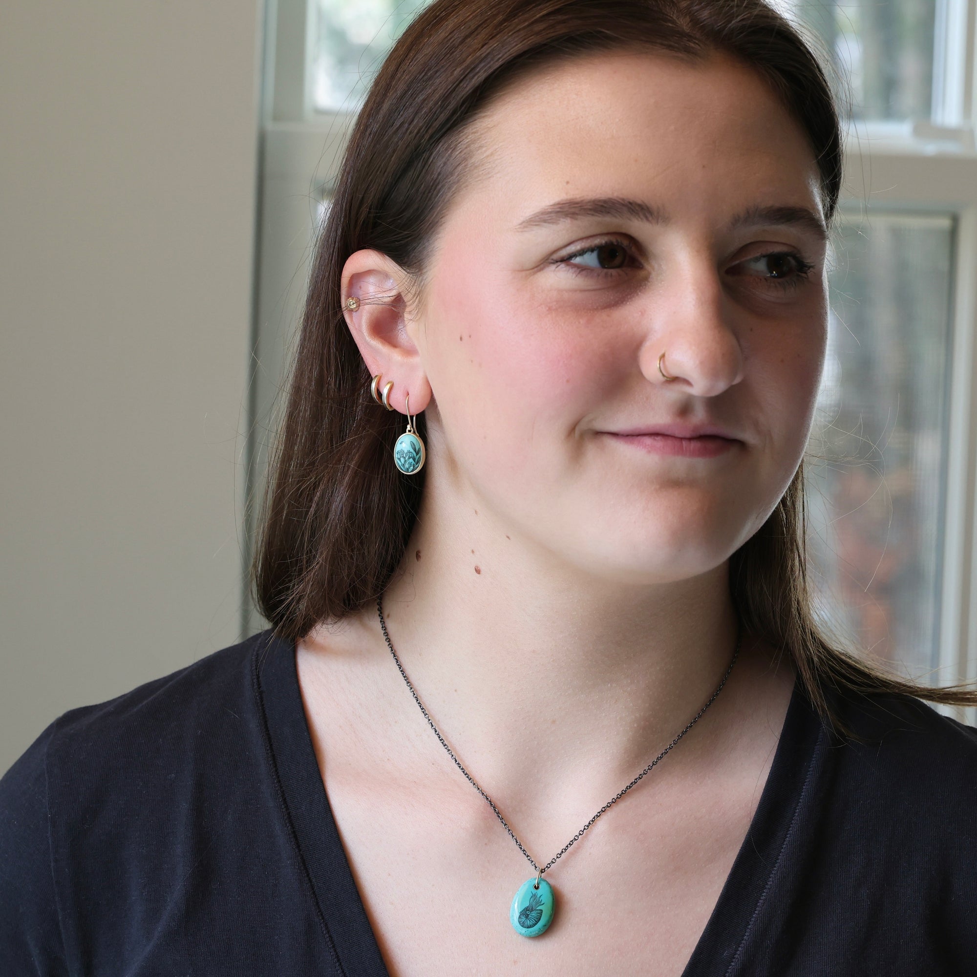 Woman wearing turquoise earrings and a necklace indoors