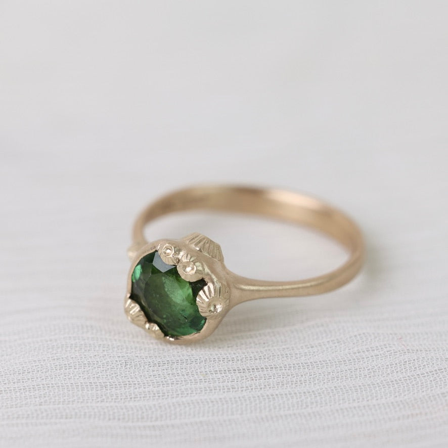 Gold ring with green gemstone on a white background