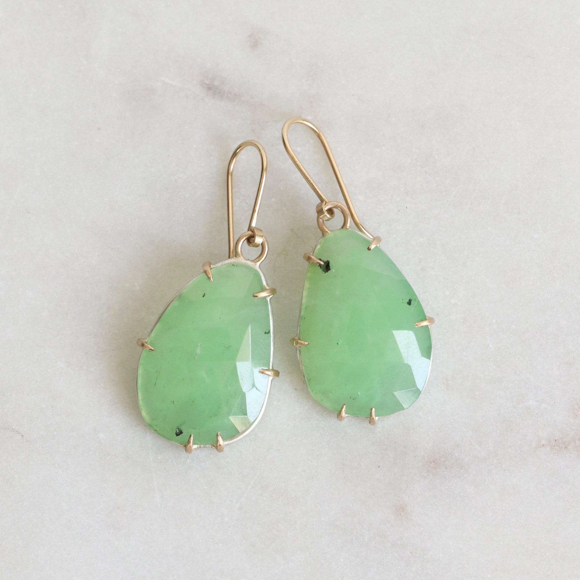 Pair of green teardrop earrings against a light gray background