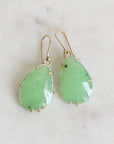 Pair of green teardrop earrings against a light gray background