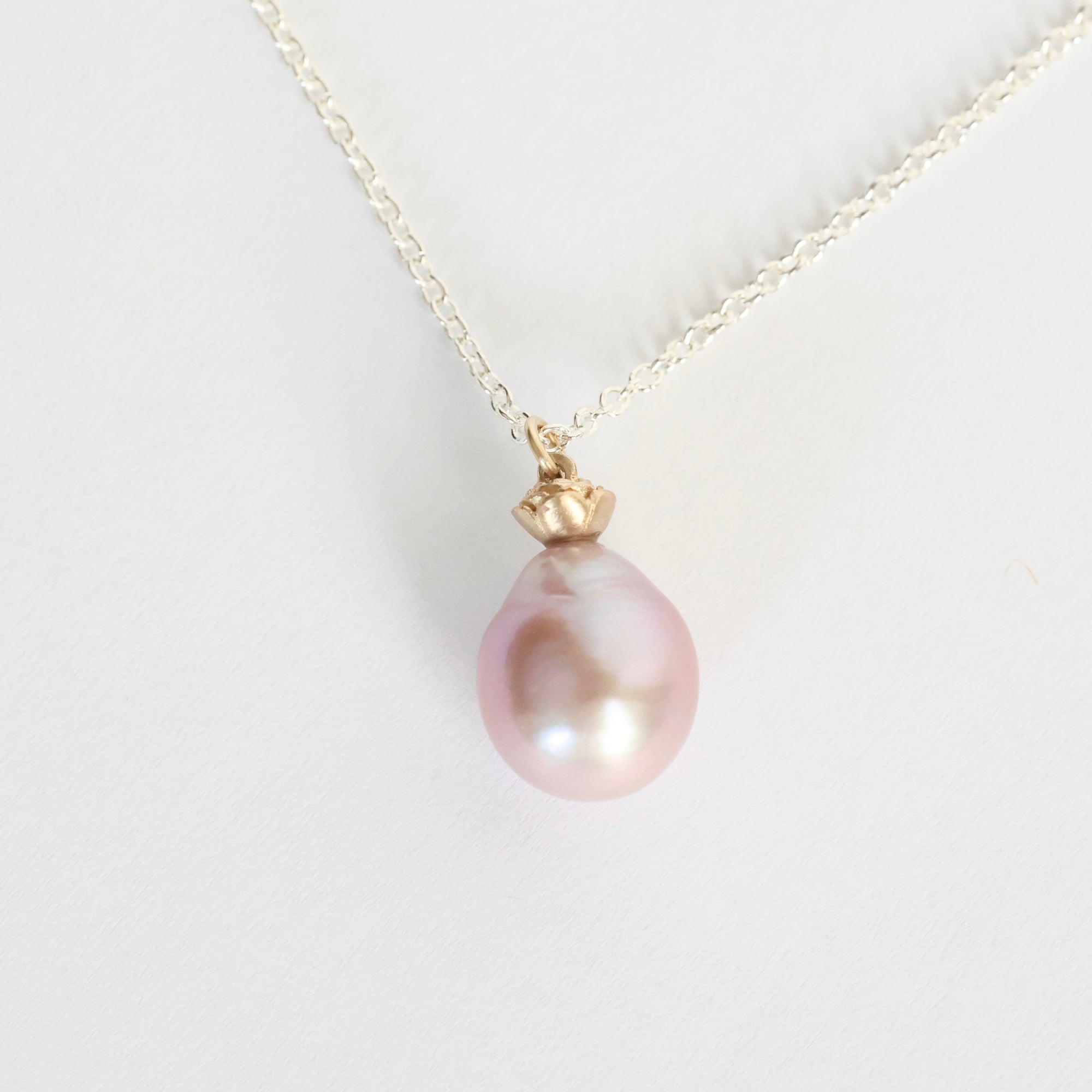 Pearl necklace with a gold clasp on a light gray background