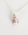 Pearl necklace with a gold clasp on a light gray background