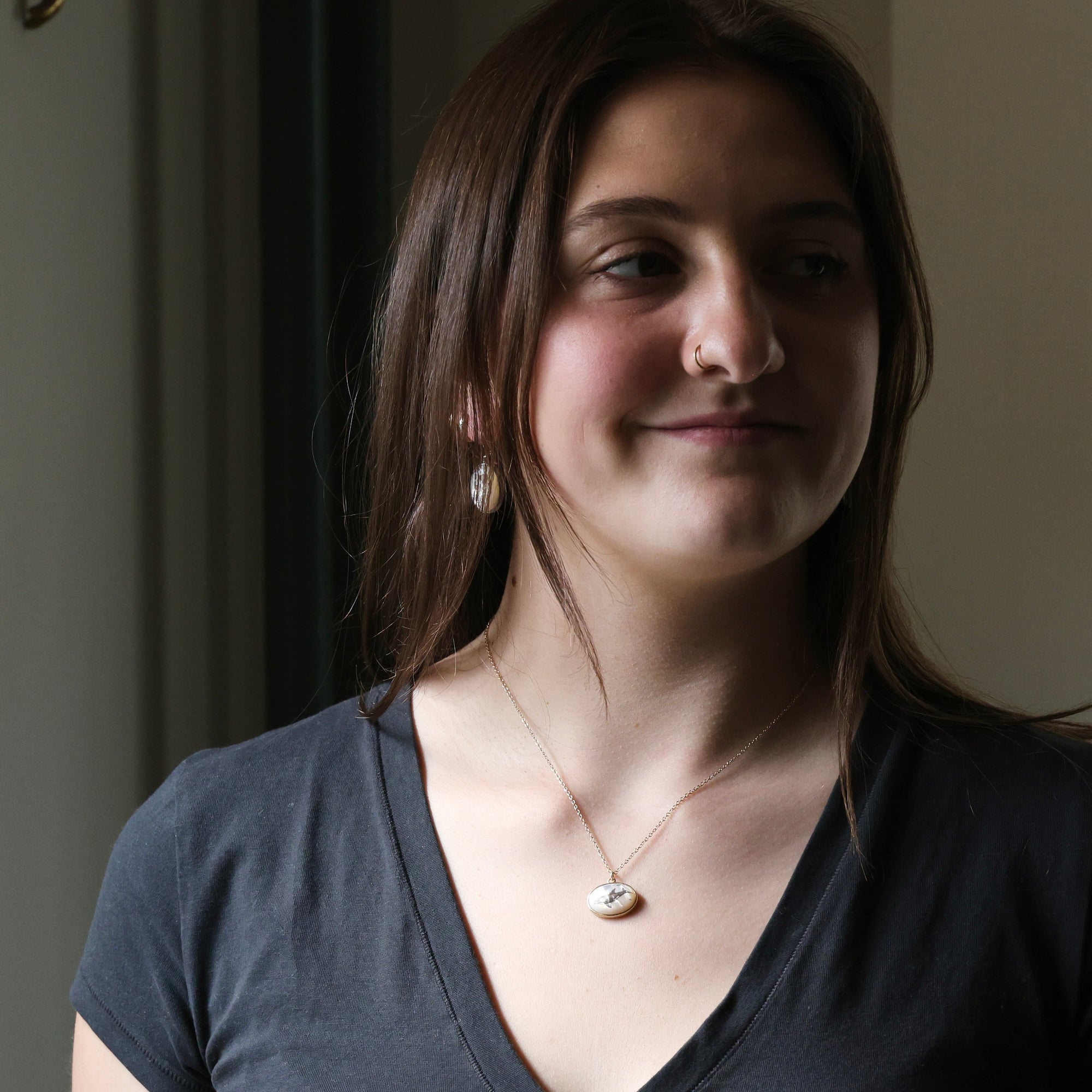 Woman wearing a necklace with a pendant indoors