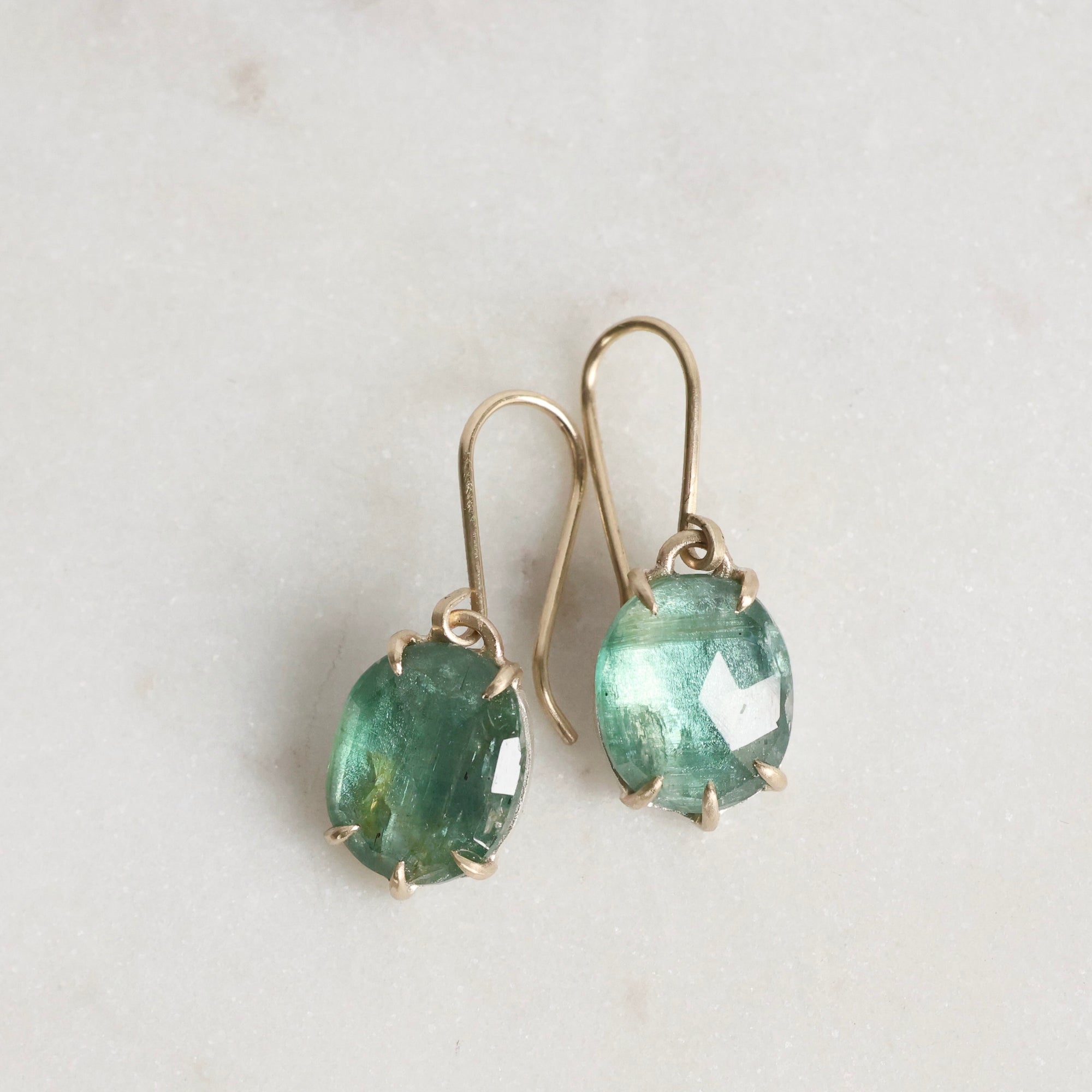 Green gemstone earrings on a light gray background
