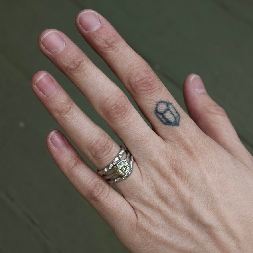 Hand with a silver ring and a small tattoo on a neutral background