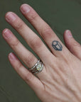 Hand with a silver ring and a small tattoo on a neutral background