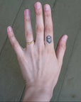 Hand with a gold ring and hexagonal tattoo on a neutral background
